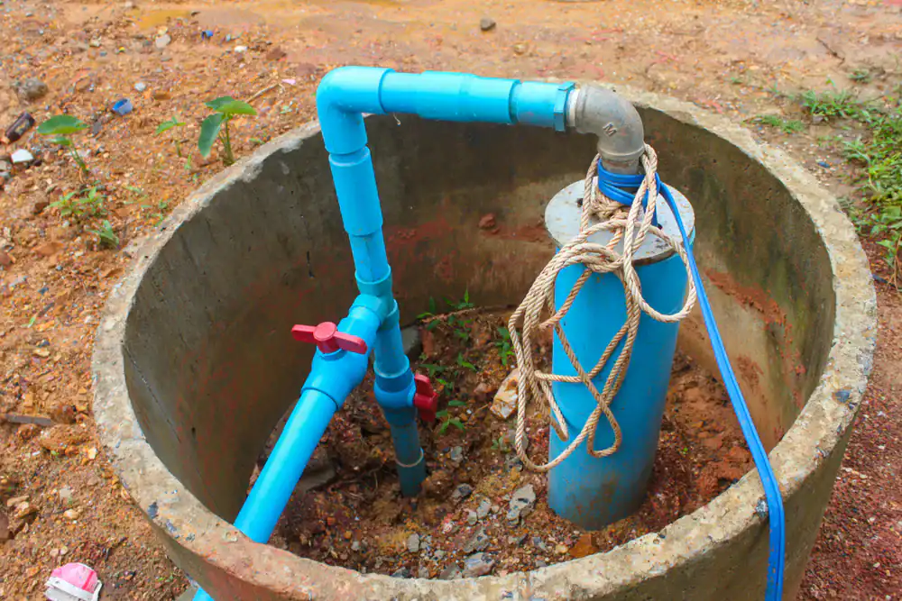 A makeshift outdoor well pump with blue PVC pipes and a rope sits in an open concrete ring, representing an alternative water source in Lake County, FL.